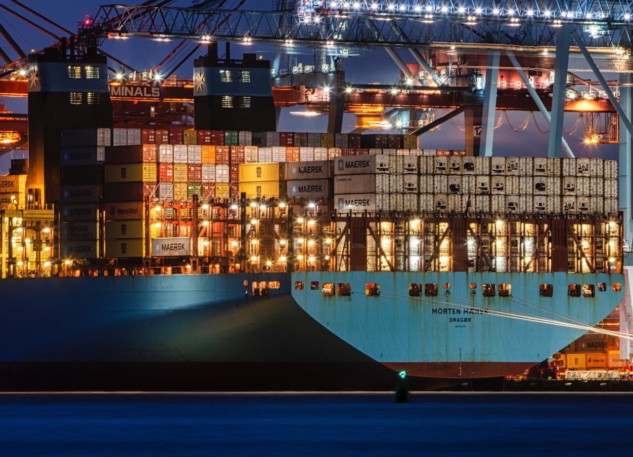 A lit cargo ship loaded with containers docked at Gothenburg harbor, showcasing the bustling night operations.